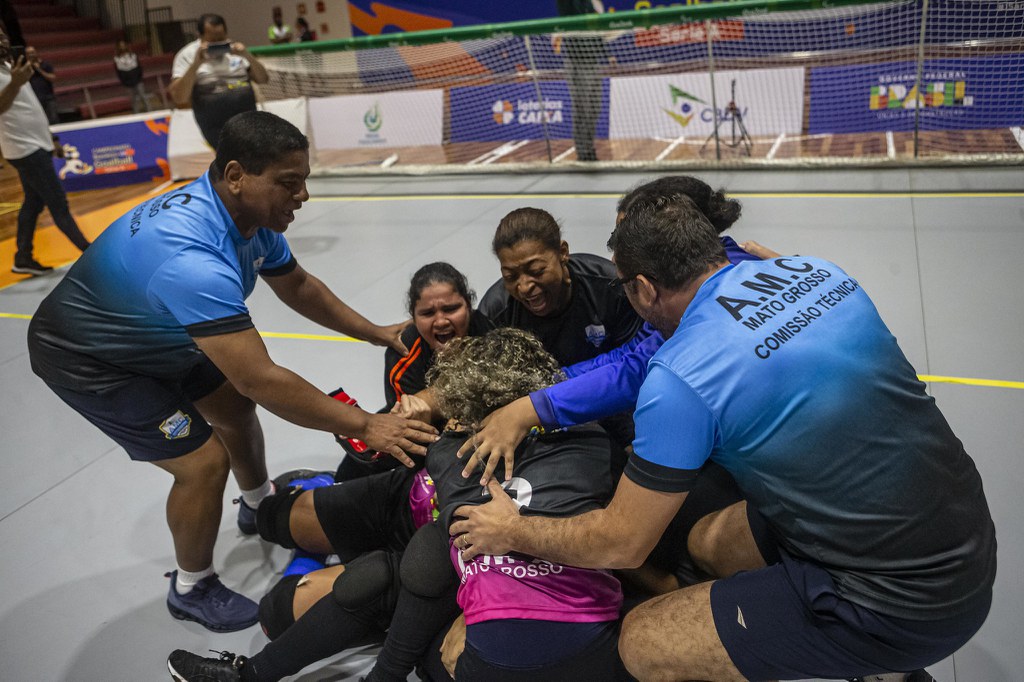 Jogadoras e comissão técnica da AMC se abraçam, no chão da quadra, em comemoração. Algumas atletas choram (Foto: Taba Benedicto/CBDV)