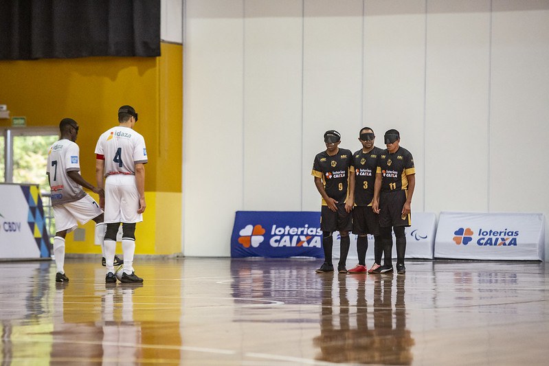 Maestro x Adef Campeonato Brasileiro de futebol de cegos Tiago Paraná e Maurício Dumbo, de branco, estão posicionados para cobrar falta. Ao fundo, três jogadores da Adef, de preto, fazem a barreira.